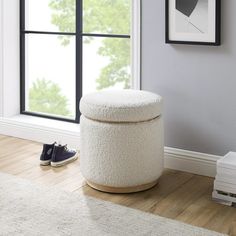 a white ottoman sitting on top of a hard wood floor next to a large window