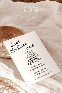 a card with the words save the date written on it next to a bowl and some dried grass