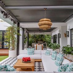 an outdoor living area with white couches and blue pillows on the floor, surrounded by greenery