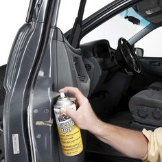 a man opening the door of a car with a can of cleaner next to it