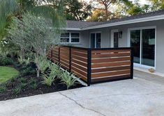 a house with a wooden fence in front of it and palm trees on the other side