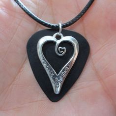 "Scrolled Heart Charm Guitar Pick Necklace Very Cute -- The overall length of the necklace is adjustable, approximately 18.25\"-19.75\" range -- The charm is made with a metal charm on a solid color guitar pick backer -- an eye catching look! The finished charm measures 1.25\"h x 1\" wide overall -- the charm hangs loose on the front of the guitar pick, so they rotate independently of one another -- The necklace cable is black 2mm dia. jewelry cord with crimped end connectors, high quality hardw Adjustable Metal Heart Necklace For Valentine's Day, Nickel Free Heart Shaped Jewelry For Festivals, Nickel-free Heart-shaped Jewelry For Festival, Handmade Adjustable Jewelry For Concert, Adjustable Music-themed Jewelry For Concerts, Adjustable Metal Heart Necklace For Gift, Adjustable Necklace For Valentine's Day Festival, Valentine's Day Metal Jewelry For Concert, Nickel-free Jewelry For Valentine's Day Festival