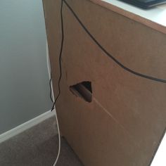 an open cardboard box sitting on the floor next to a laptop computer and wires in it