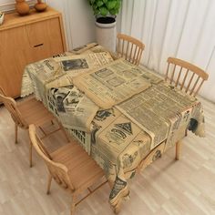 a dining room table covered in newspaper paper with wooden chairs and a potted plant