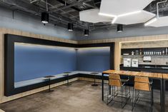 an empty room with tables and stools next to a wall mounted projector screen