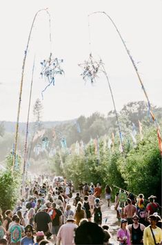 a crowd of people walking down a street next to trees