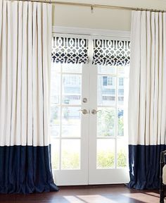 a living room with white and blue drapes on the windowsills, an arm chair in front of a door