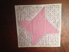 a pink and white quilted star on a wooden floor