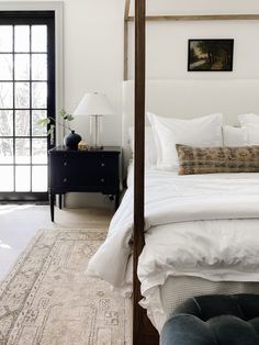 a bed with white linens and pillows in a bedroom next to a black door