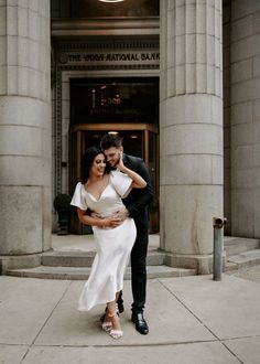 a man and woman standing in front of a building