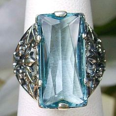 Sky Blue Aquamarine Ring Baguette Design#32 Introducing the Baguette D32, a stunning piece of wearable art that pays homage to the opulent Victorian era. Crafted with meticulous attention to detail, this exquisite filigree Antique reproduction in sterling silver is sure to captivate anyone with a love for vintage-inspired jewelry. At its center, lies a flawless 7ct sky blue gemstone, radiating a dazzling hue that catches the light with every movement. The baguette rectangle-cut gemstone measures Rectangular Aquamarine Jewelry For Wedding, Blue Aquamarine Jewelry With Rectangular Stone, Rectangular Aquamarine Blue Jewelry, Rectangular Aquamarine Wedding Jewelry, Rectangular Blue Aquamarine Jewelry, Blue Rectangular Aquamarine Jewelry, Elegant Aquamarine Blue Jewelry, Elegant Blue Aquamarine Jewelry, Rectangular Light Blue Jewelry Gift