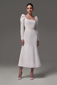 a woman wearing a white dress with long sleeves and an asymmetrical neckline