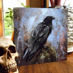 a painting of a black bird sitting on top of a wooden table next to a skull