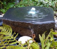 a water fountain surrounded by rocks and plants