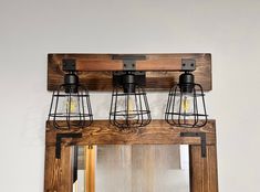 three light fixtures mounted on a wooden mirror