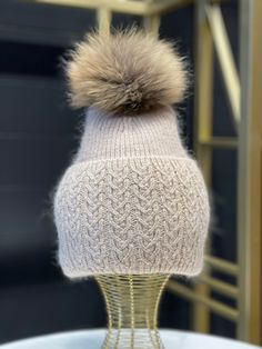 a white knitted hat with a brown pom - pom sitting on top of it