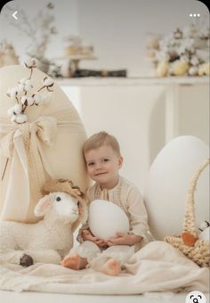 a little boy holding an egg next to some stuffed animals