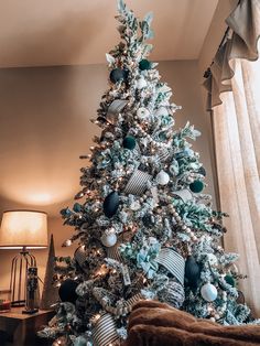 a decorated christmas tree in a living room with blue and silver ornaments on the top