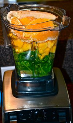 a blender filled with oranges and green leaves