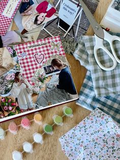 the table is covered with many crafting items including scissors, fabric, and paper