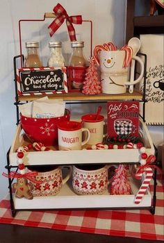 a shelf filled with coffee mugs and other christmas items on top of a checkered table cloth