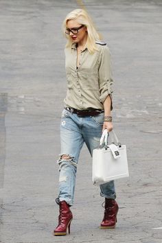 a woman in ripped jeans and red boots carrying a white handbag