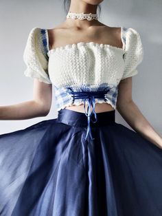 a woman in a blue and white dress with her hands on her hips wearing a choker necklace