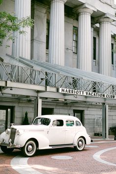 an old white car is parked in front of the marriott vacation club building