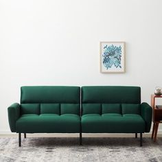 a green couch sitting on top of a rug next to a table