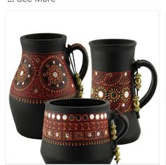 three black and red vases with designs on the sides, one has a beaded handle