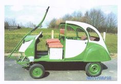 a small green and white car parked in a parking lot next to a grassy field