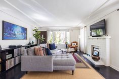 a living room filled with furniture and a flat screen tv mounted on the wall above a fire place