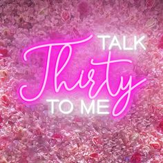 a pink neon sign that says talk thirty to me on it's side, surrounded by flowers