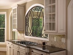 a kitchen with an arched window and marble counter tops in front of the stove top