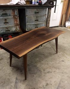 a wooden table sitting on top of a floor in a room filled with drawers and other furniture