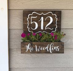 a wooden sign that says, the weedkins is 512 and has flowers in it