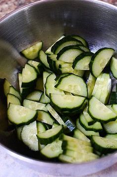 a metal bowl filled with sliced cucumbers