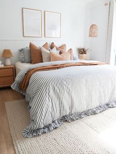 a bedroom with white walls and striped bedding in the corner, along with two framed pictures on the wall