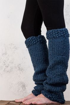 a woman's legs in knitted leg warmers on top of a wooden floor