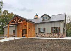 a large gray house with a metal roof and stone wall around the front porch area