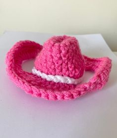 a pink crocheted hat with a white band