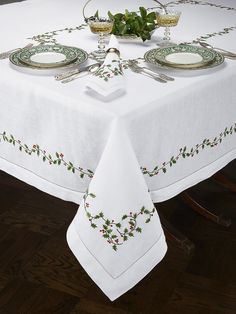 a white table cloth with holly design on it and two place settings at the top