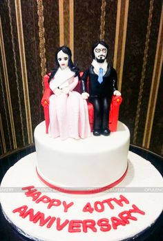 a cake that has two people sitting on top of it, and the words happy 60th anniversary written in red