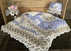 a crocheted blanket and hat are sitting on a wooden chair next to a teddy bear