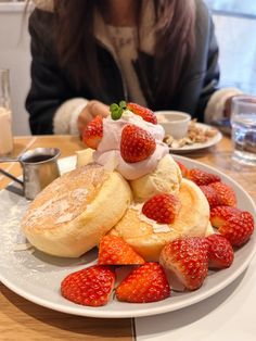 a woman sitting at a table with a plate of food and strawberries on it