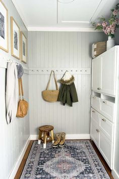 a hallway with a rug, shoes and purses hanging on the wall next to it