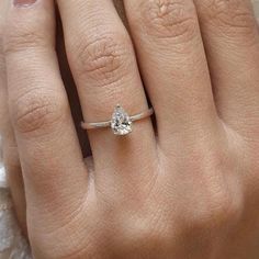 a woman's hand with a white diamond ring on her finger and an engagement band