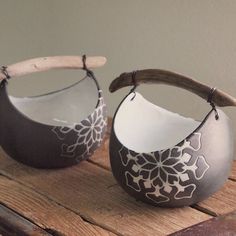 two silver vases sitting on top of a wooden table with white flowers painted on them