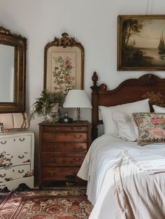 a bed sitting in a bedroom next to two dressers with mirrors on top of them