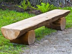 a wooden bench sitting on top of a grass covered field next to a tree trunk